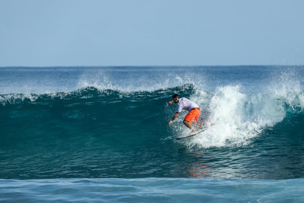 Surfer riding a wave in Fernando de Noronha, Brazil, showcasing vibrant ocean action in summer.