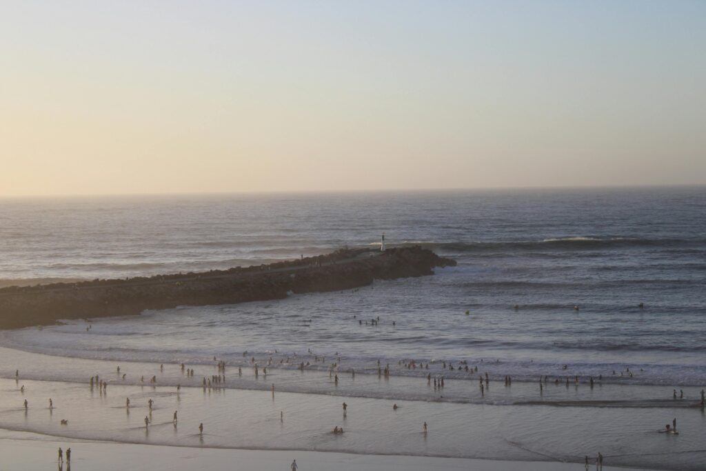 Serene view of Rabat beach during sunset with silhouettes of people enjoying the water.